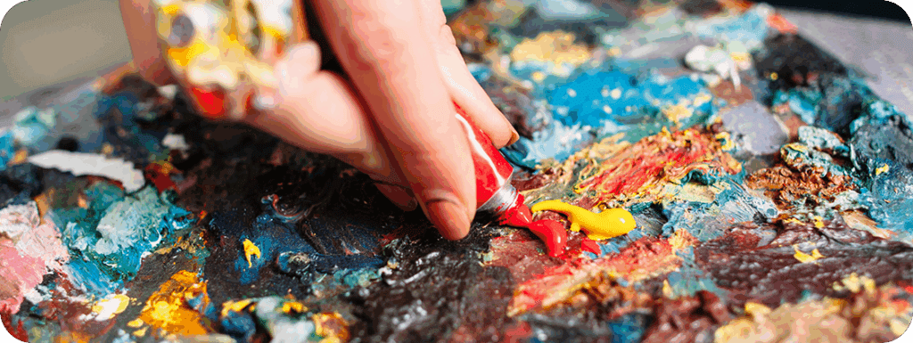 An artist mixing paint on their palette