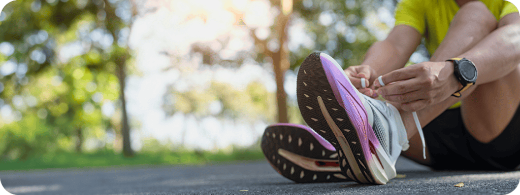 A runner lacing up their shoes outdoors